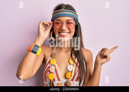 Belle femme hispanique portant le style bohème et hippie souriant heureux en pointant avec la main et le doigt sur le côté Banque D'Images
