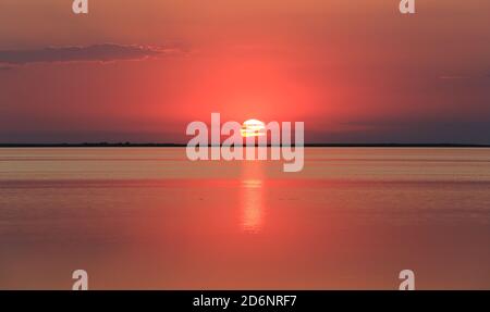 grand soleil sur la surface de l'eau de mer pendant le coucher du soleil Banque D'Images