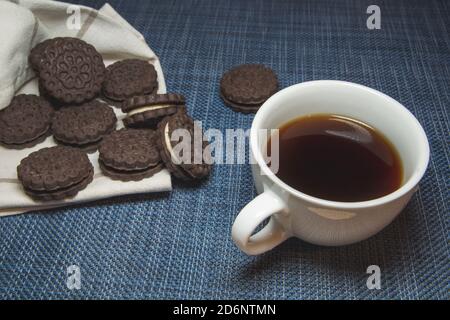 Café dans une tasse et biscuits sur fond bleu Banque D'Images