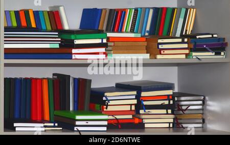Pile de divers carnets ou livres en cuir dans un bibliothèque grise Banque D'Images