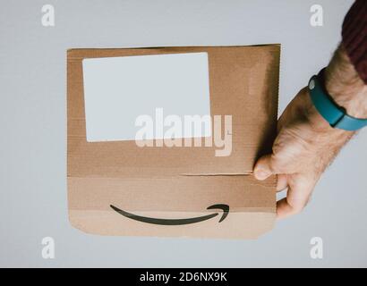 Paris, France - 14 mars 2018: Homme tenant main Amazon Prime carton paquet montrant le logotype insignia - isolé sur blanc Banque D'Images