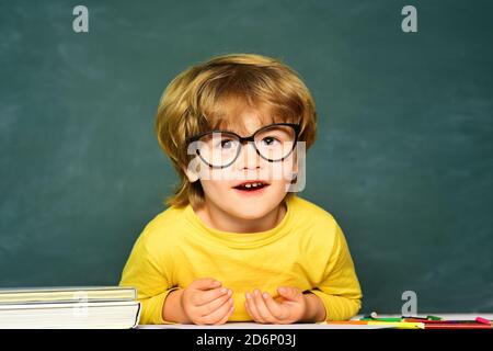 Petit garçon étudiant heureux avec une excellente marque. Mignon petit garçon d'âge préscolaire dans une salle de classe. Joli garçon avec une expression du visage heureux près du bureau avec Banque D'Images