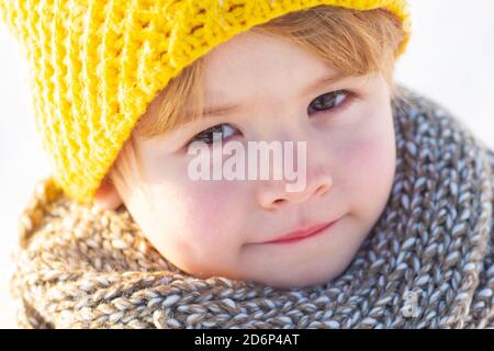 Mignon petit garçon enfant dans les vêtements d'hiver marchant sous la neige. Enfant en veste bleue et chapeau jaune marche dans la forêt enneigée écoute les sons de la nature Banque D'Images