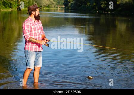 Homme pêche. Pêche à la mouche en utilisant la canne de pêche à la mouche dans la belle rivière. Homme avec des cannes à pêche sur le quai de la rivière. Concepts de pêche réussie. Banque D'Images