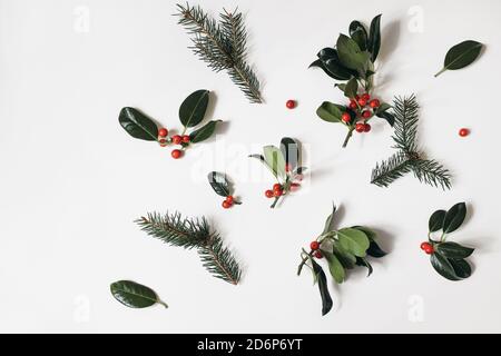 Motif fleuri de Noël. Cadre de bordure des baies de houx rouge et des branches d'épinette verte isolées sur fond de table blanc. Hiver naturel Banque D'Images