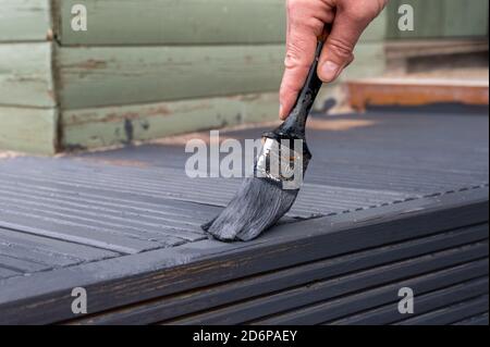 Femmes peinture mains défraîchi vieux jardin lames de terrasse en bois avec gris Peinture Banque D'Images