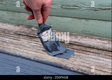 Femmes peinture mains défraîchi vieux jardin lames de terrasse en bois avec gris Peinture Banque D'Images