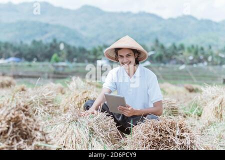 l'agriculteur sourit tout en montrant les rendements de la récolte de riz quand utilisation d'un tablet pc dans les champs Banque D'Images