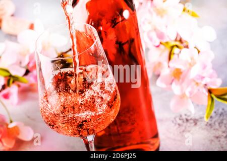 Vin de rose sortant de la bouteille, bakcGround gris, fleurs roses. Dégustation de vins de Rosado, rosato ou blush au wineshop, concept de bar. Copier l'espace Banque D'Images