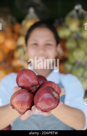 Des pommes rouges fraîches dans les mains d'un magasin de fruits commis à un kiosque à fruits Banque D'Images