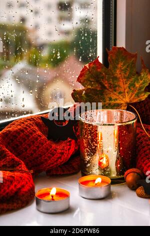 Bougies avec chandail et potiron fantôme, feuilles séchées sur le rebord de la fenêtre. Décoration de la maison d'Halloween. Fenêtre de pluie. Banque D'Images