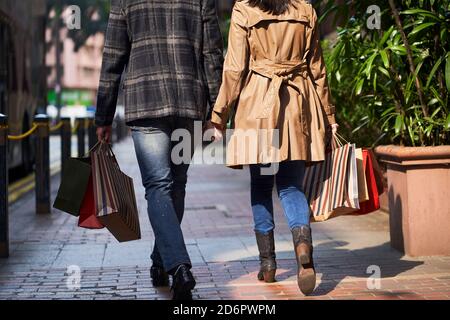 vue arrière de jeune couple asiatique marchant dans la rue avec sacs à provisions dans les mains Banque D'Images