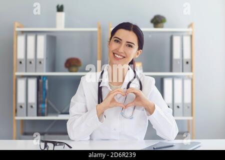 Femme médecin montrant un geste cardiaque à l'intérieur. Cardiologue communiquant en ligne. Santé cardiaque, organisme de bienfaisance ou don Banque D'Images