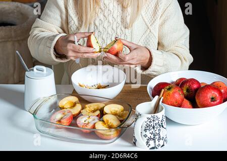 les mains des femmes coupent une pomme et la préparent pour la cuisson, sur la table dans un bol blanc avec des pommes, concept de cuisson fait maison pour les vacances Banque D'Images