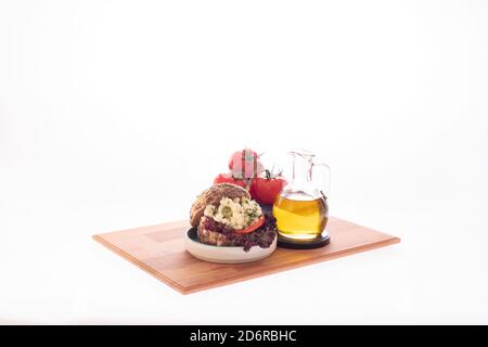 Sandwich au fromage blanc et au tomatoe avec une bouteille d'olive huile et un bouquet de tomates servi assiette en bois Banque D'Images
