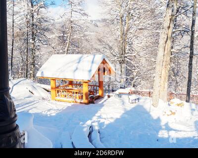 Vue sur un belvédère en bois situé sur un pré couvert de neige parmi les arbres dans les montagnes Banque D'Images