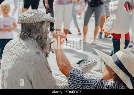 12.08.2019, Porto, Potugal. Vieilles femmes faisant une sculpture d'un cordonnier réparant des chaussures et des bottes. Artistes de rue, artistes de rue jouent dans la rue Banque D'Images