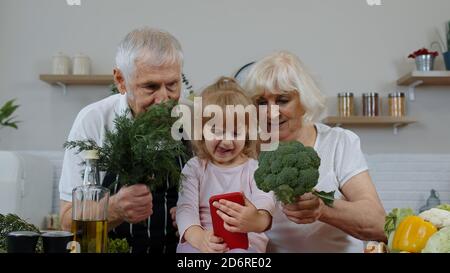 Blogueur enfant fille prenant des photos au téléphone avec des grands-parents de couple senior, faisant selfie à des comptes sociaux ou des histoires vidéo. Prendre des photos, prendre des selfies pour les médias sociaux sur smartphone dans la cuisine Banque D'Images