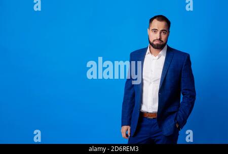 Jeune homme dans un costume bleu classique sur un bleu arrière-plan Banque D'Images