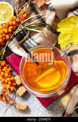 Boisson saine de vitamine d'automne. Thé d'argousier chaud avec citron et baies d'argousier fraîches sur un comptoir en pierre. Vue de dessus de l'arrière-plan de la mise à plat Banque D'Images