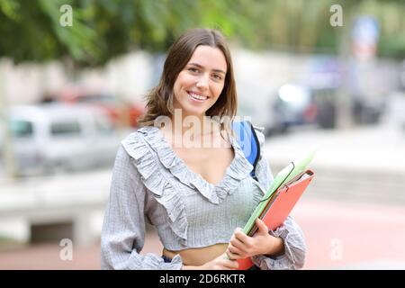 Heureux étudiant posant regardant la caméra avec des dossiers debout la rue Banque D'Images