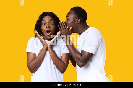 Un gars noir partageant le secret avec sa petite amie stupéfaite Banque D'Images