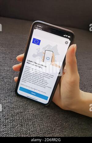 19 octobre 2020, Berlin: Une femme possède un iPhone avec la version actuelle de l'application d'avertissement Corona, enregistrée lundi (19.10.2020) l'application Corona-WARN du gouvernement fédéral allemand peut désormais également avertir d'une rencontre potentiellement dangereuse avec des personnes infectées par le corona à travers les frontières. Comme annoncé, la mise à jour de la version 1.5 est apparue dans les App Stores de Google et Apple lundi après-midi. Cela signifie que les contacts avec les utilisateurs des applications officielles de Corona d'autres pays peuvent désormais être identifiés lors de l'évaluation des risques. Photo: Christoph Dernbach/dpa Banque D'Images
