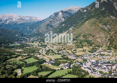 Ciel bleu clair sans nuages sur de longues allées étroites entourées par pistes de montagne couvertes d'arbres et d'herbe verdoyante Banque D'Images