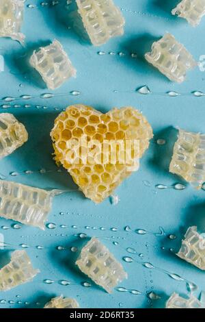 De dessus de coeur brillant en forme de nid d'abeille avec le miel délicieux sur fond bleu Banque D'Images