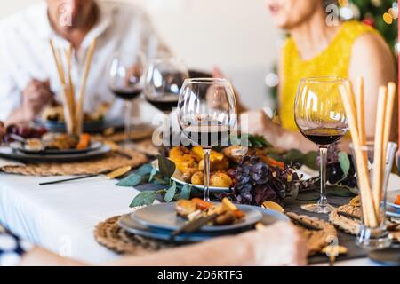 Table de salle à manger servie avec des verres et des assiettes contre les flous luminescents Sapin de Noël la veille de Noël à la maison Banque D'Images
