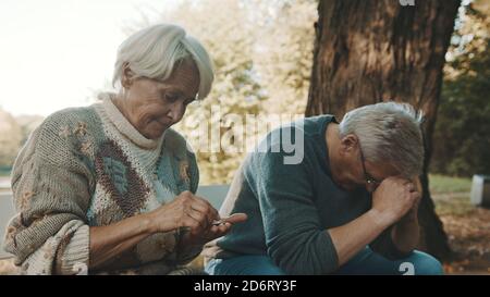 Les personnes âgées craignaient un couple assis sur le banc dans le désespoir. Femme comptant les dernières pièces. Photo de haute qualité Banque D'Images