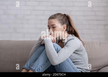 Jeune femme souffrant de dépression assise seule sur un canapé à la maison Banque D'Images