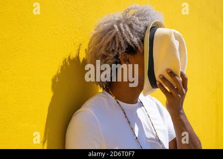 Homme noir aux cheveux d'afro se couvrant avec un chapeau sur son visage. Concept de chapeau de paille. Banque D'Images