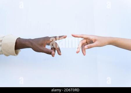 Rognez un homme et une femme divers et méconnaissables en touchant les index contre un fond blanc Banque D'Images