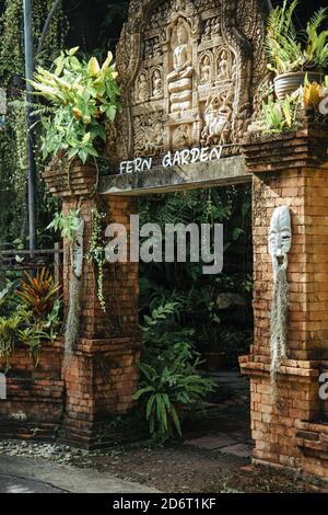 Thaïlande - 2019. Jardin botanique de Phuket. Statue de trois garçons tenant une belle plante bordeaux. Arrière-plan flou pour l'idée artistique. Banque D'Images