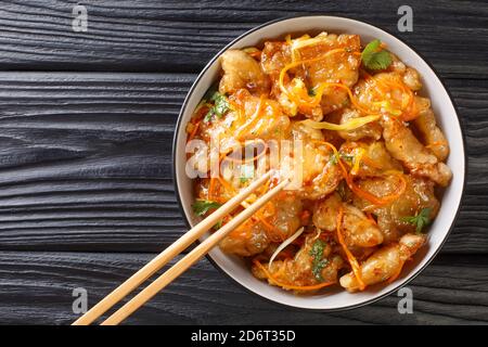 Porc chinois en sauce aigre-douce avec carottes, oignons, ail et gingembre dans un bol sur la table. Vue horizontale du dessus Banque D'Images