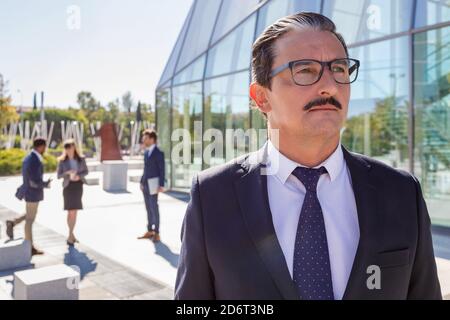 Un homme sérieux d'âge moyen avec une moustache dans une tenue élégante regarder loin tout en pensant à la stratégie d'affaires dans la rue Banque D'Images
