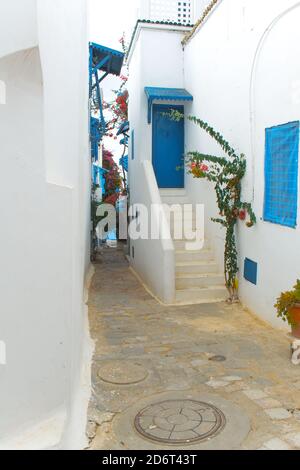 Une rue étroite de style architectural méditerranéen avec des fenêtres et des portes bleues et blanches. Tunisie Banque D'Images