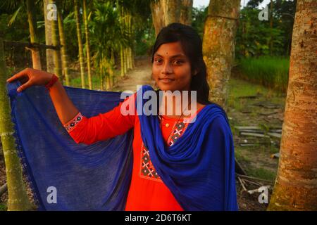 Gros plan d'une adolescente portant salwar kameez et la dhupatta bleue de la main droite sur son cou, debout sur un champ de riz, focalisation sélective Banque D'Images