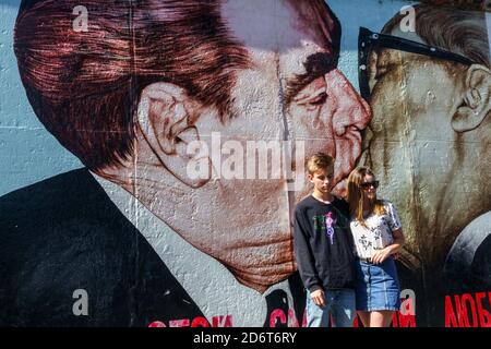 Jeune couple à Graffiti sur la section originale de Berlin Mur à l'East Side Gallery Friedrichshain Berlin Allemagne graffiti art de rue wall city Banque D'Images