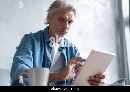 Beau homme d'affaires travaillant sur une tablette de la maison. Banque D'Images