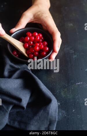 Du dessus de la récolte anonyme mâle cuire mélange de cassis mûr baies dans un bol en céramique noire dans la cuisine Banque D'Images