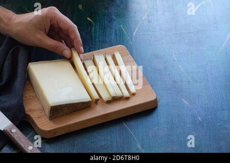 D'en haut homme anonyme prenant une tranche de doux délicieux Camembert fromage coupé sur bois et placé sur une table noire Banque D'Images