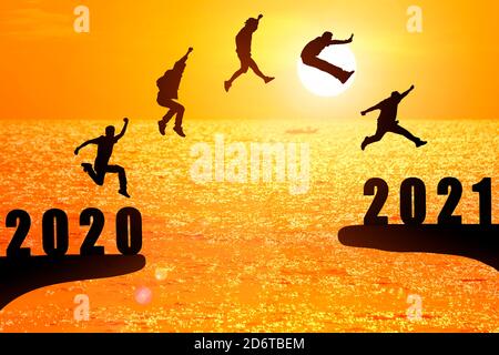 Groupe silhouette de jeunes gens sautant entre 2020 et 2021 ans avec beau coucher de soleil sur la mer. Banque D'Images