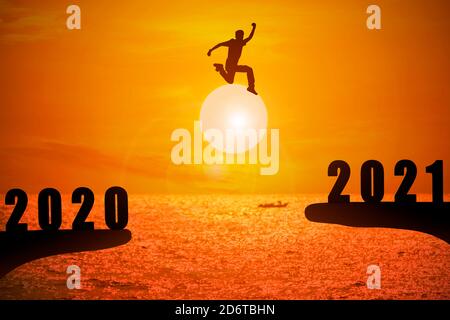 Silhouette de jeune homme sautant entre 2020 et 2021 ans avec beau coucher de soleil sur la mer. Banque D'Images