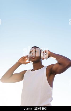 De dessous le portrait d'un coureur sérieux afro-américain à l'écoute musique dans les écouteurs à l'extérieur Banque D'Images