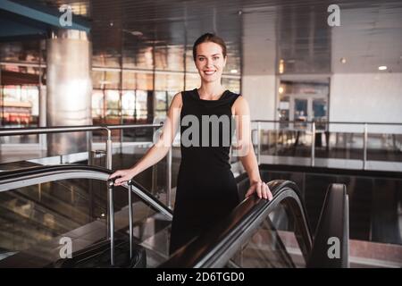 Femme élégante utilisant un escalier mécanique à l'aéroport Banque D'Images