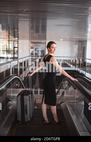 Femme utilisant un escalator pour transporter ses bagages Banque D'Images