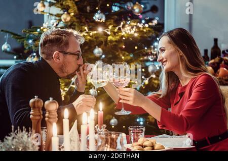 Un couple d'âge moyen boit du vin la veille de Noël Banque D'Images