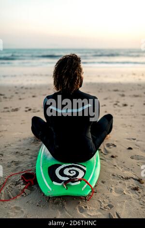 Portrait joyeux de la jeune femme afro-américaine vêque de blanc porter un casque sur le cou et regarder l'appareil photo debout en studio sombre à ne Banque D'Images